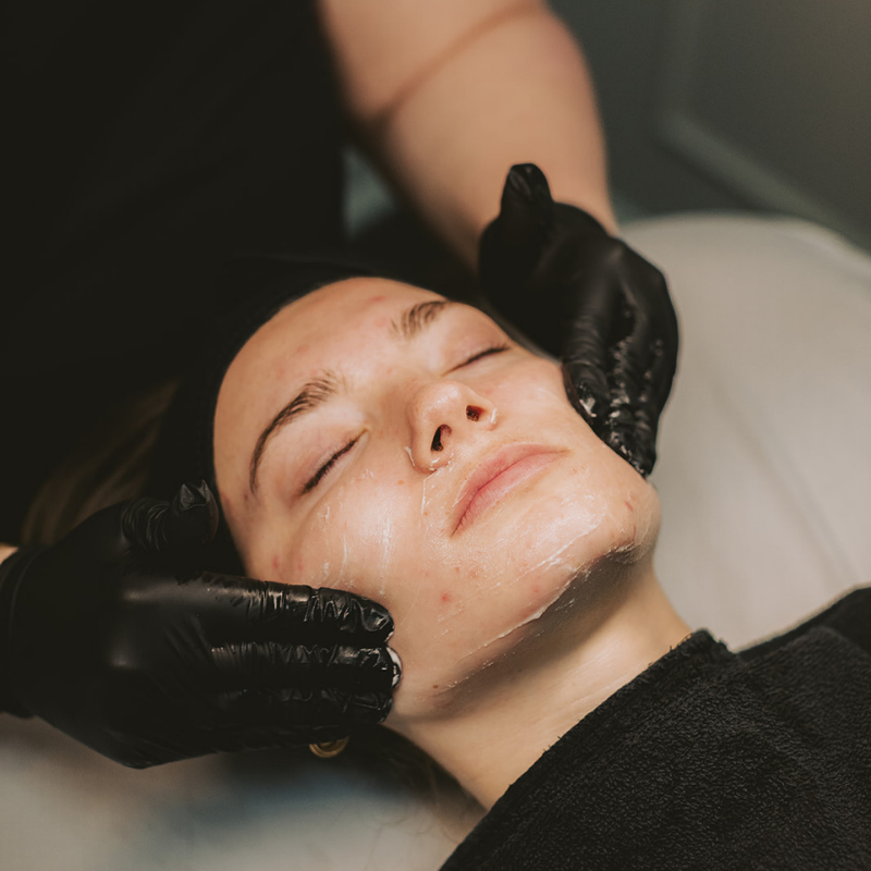 woman having her face examined by two gloved hands